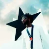 A young black man wears sunglasses and poses in front of a large black star.