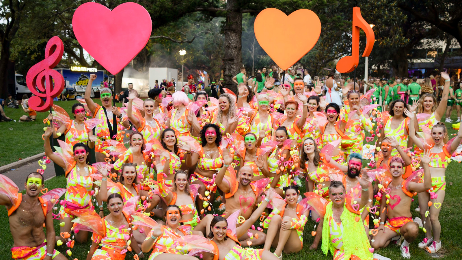 A group of people wearing neon, heart-shaped accessories posing for a picture.