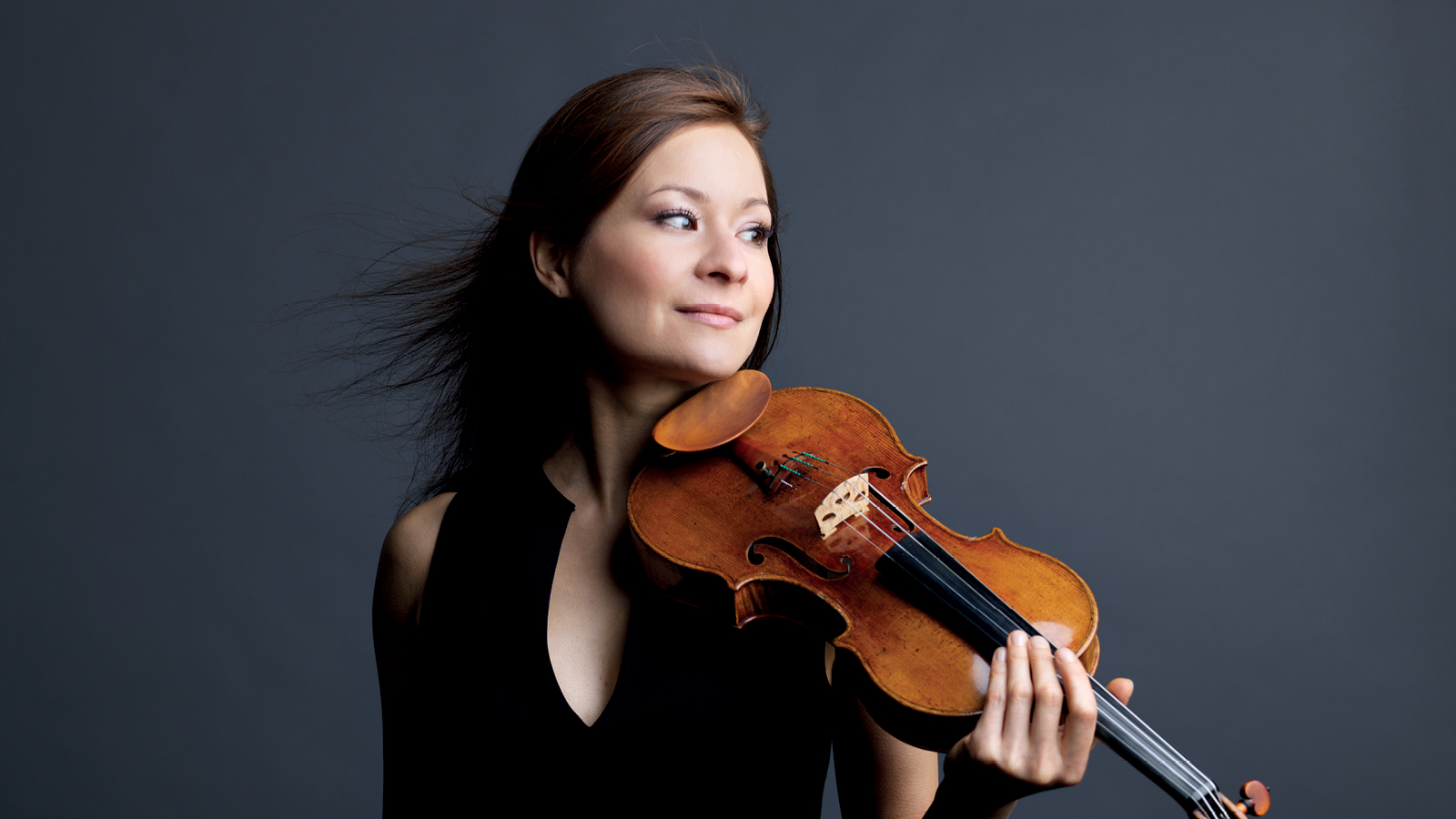 A woman with brown hairs holding a violin.