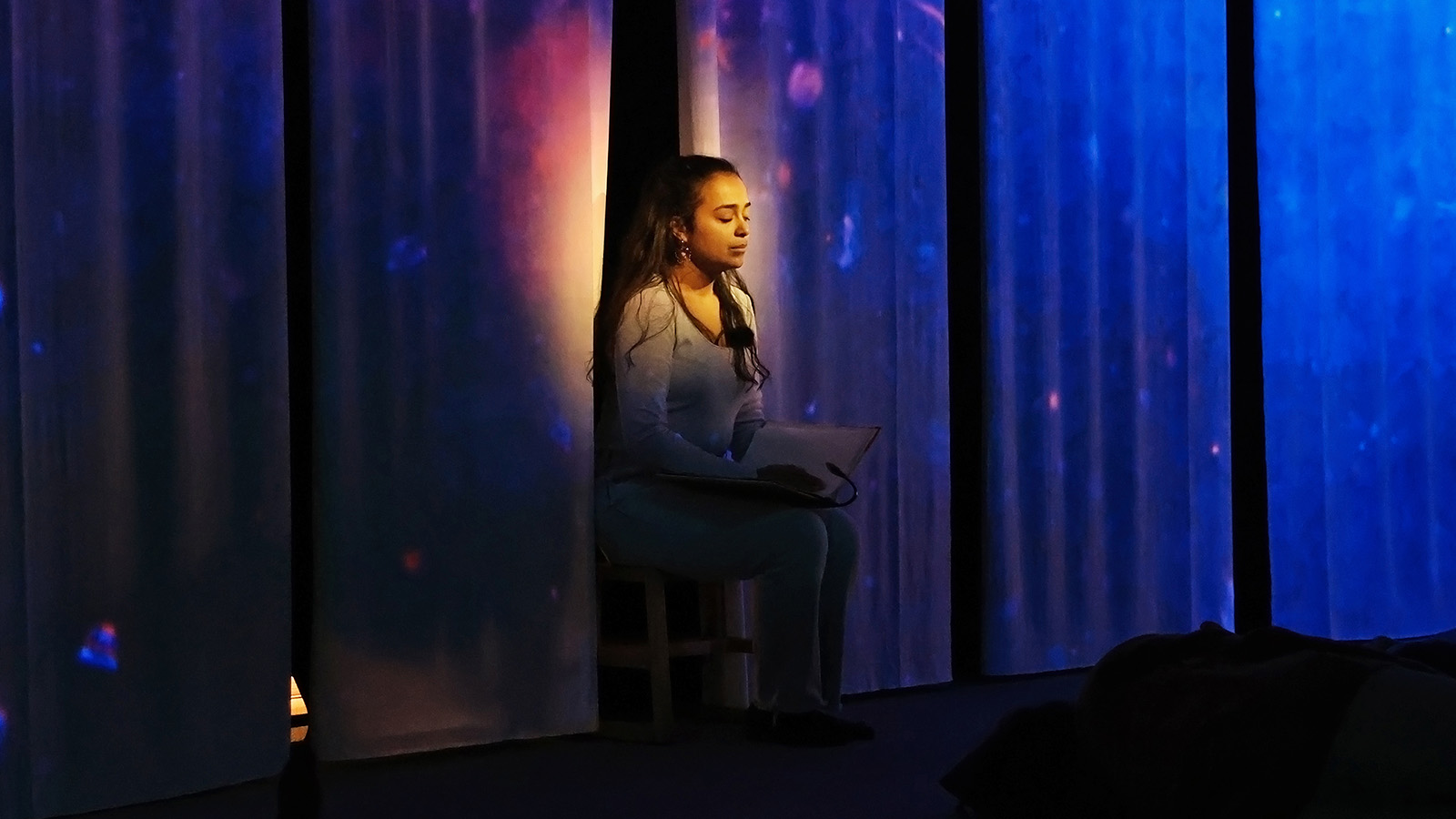 A young lady meditating in a spotlight.