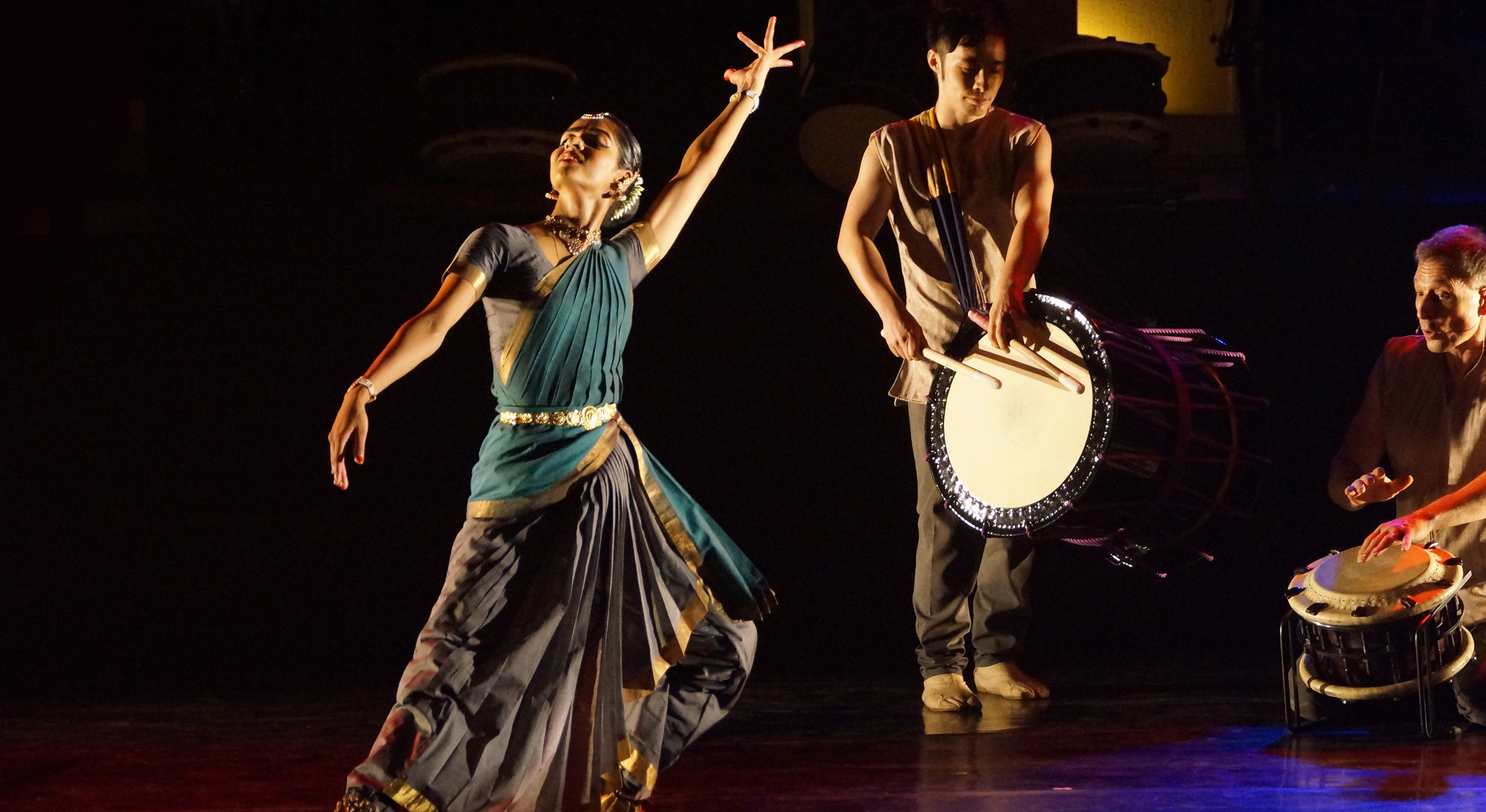 A woman in an Indian saree dancing to the sound of a Japanese drum