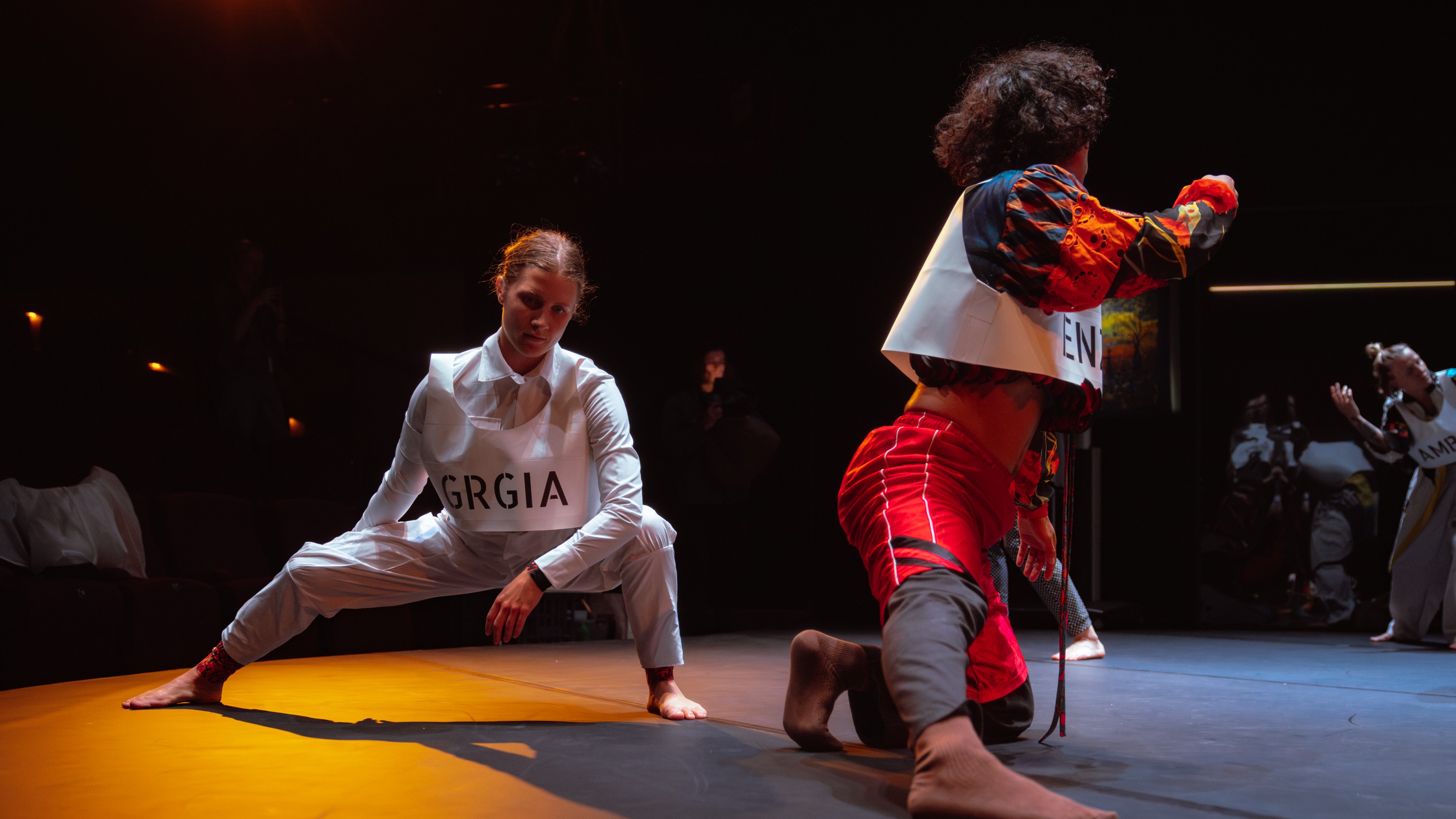 A captivating stage scene features two dancers, one in motion and the other on the ground, highlighting their expressive performance.