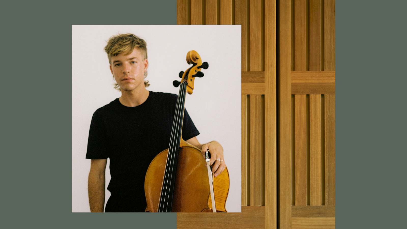 A young blonde man in black t-shirt holding a bass violin.