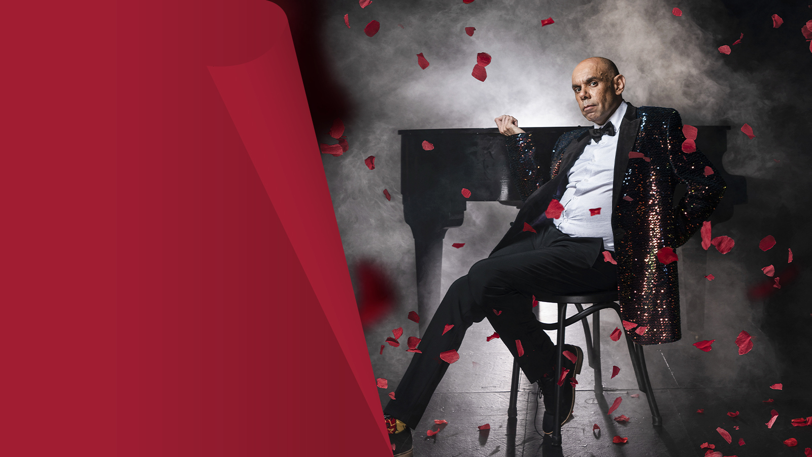 A bald man in a black suit with roses in the air.