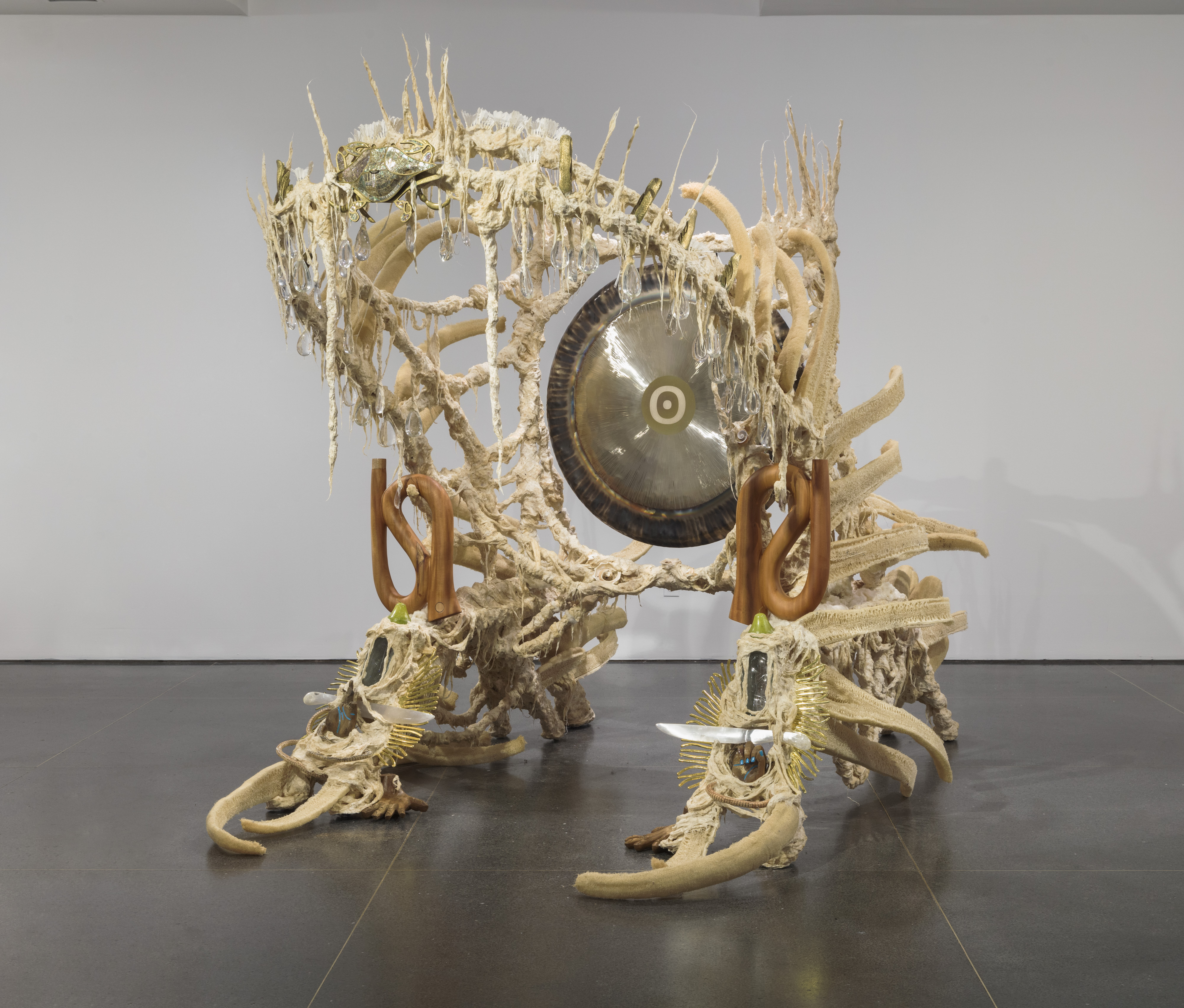 A large cream sculpture with a gong in the centre representing the artists battle with cancer in an exhibit.