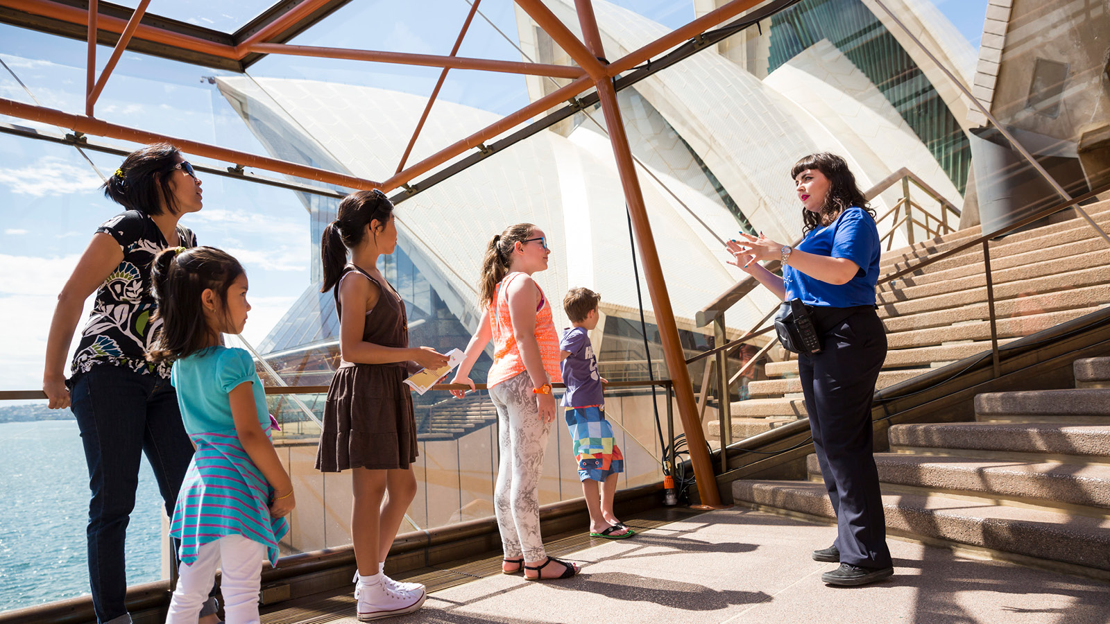 A woman giving a tour to the kids at Sydney opera house.