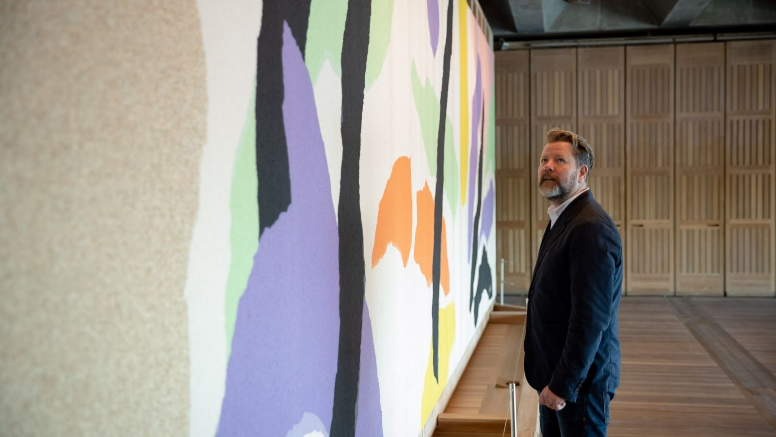 A man in a suit staring at artwork on a wall.