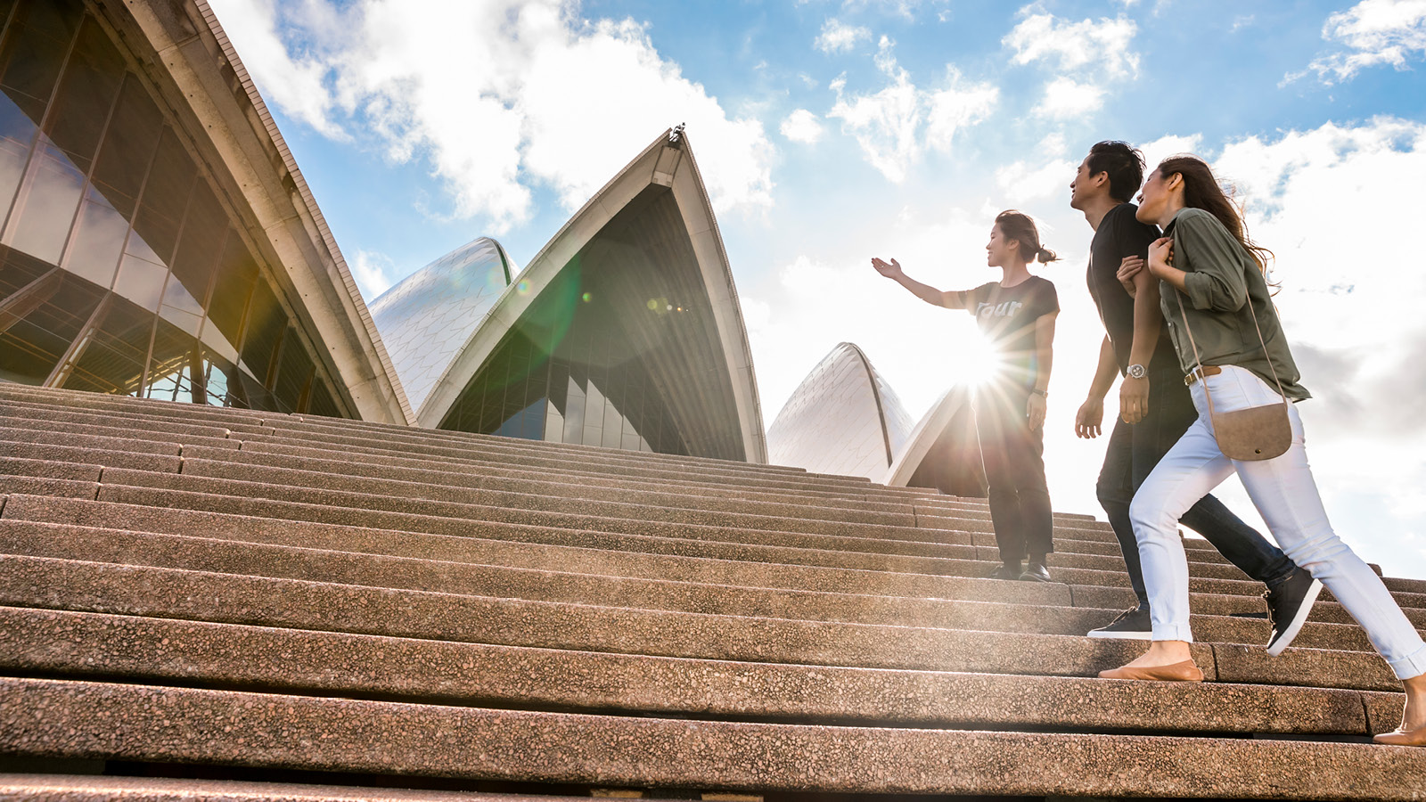 A tour guide outside Sydney opera house with a couple.