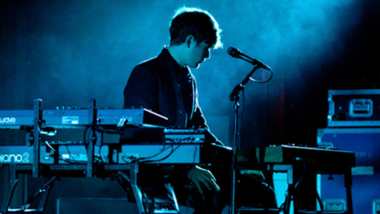 A man performing on a blue-lit stage.