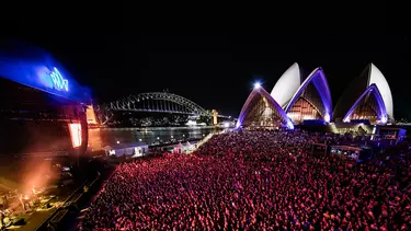 A lively audience watching a stage with views of the Sydney Opera House and Harbour Bridge.