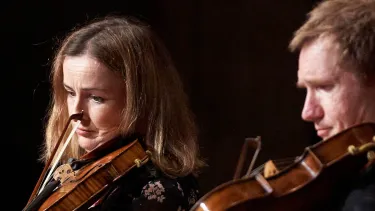 A closeup of two violin players side by side