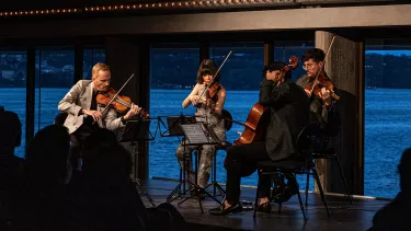 A small group of men and women playing violin in a room.