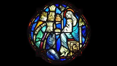 A medieval glass stained window of three kings bringing gifts to the Mother Mary and Jesus