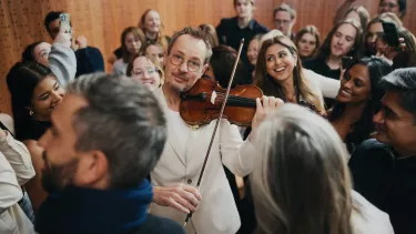 A man plays violin while the crowd encircles him.