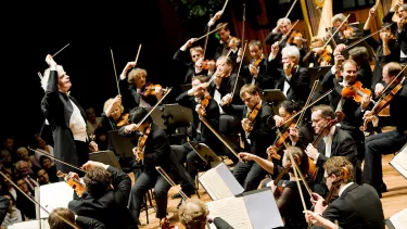 A conductor leads an orchestra on stage at the Sydney Opera House