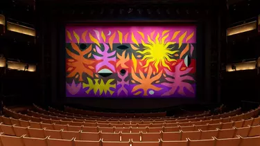 An empty theatre with the tapestry curtain closed over the stage.