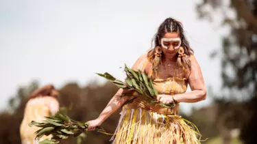 A woman with face makeup performing the Aboriginal dance rites.