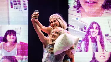 Two actors of 'Fangirls' taking a selfie on stage.