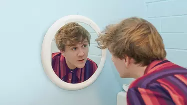 Josh Thomas staring into a mirror