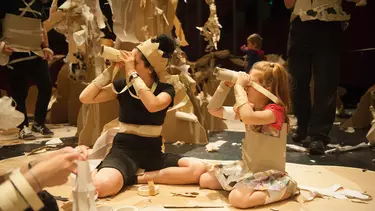 Children wearing cardboard costumes with a background of cardboard trees