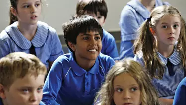 A group of children sitting inside a classroom.