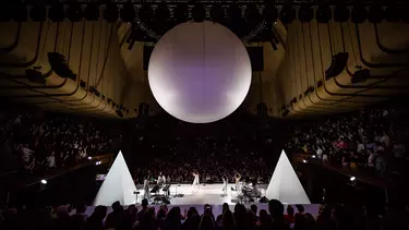 A group of musicians performing on the stage with a big balloon above them.