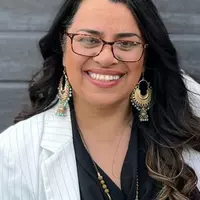 A woman in white jacket wearing earrings and necklace.