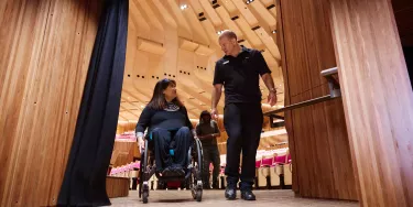 A man escorting a woman on a wheelchair.