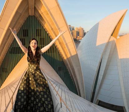An opera singer standing on the sails of the Opera House.