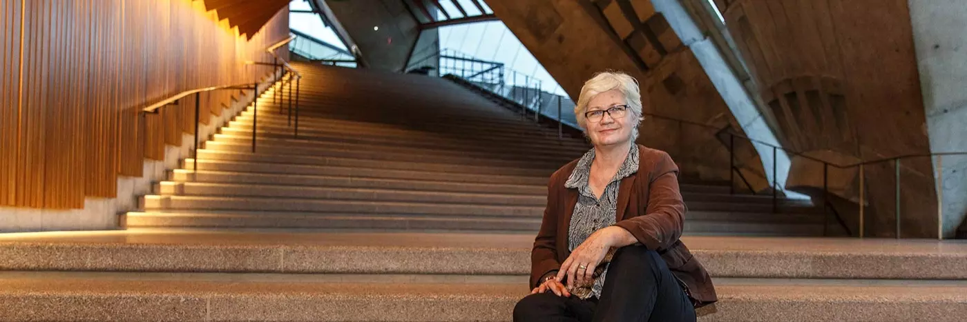 A woman sits on the stairs of the Opera House theatre foyers with her hands resting on her knees.