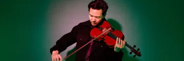 A man in black jacket playing a violin.